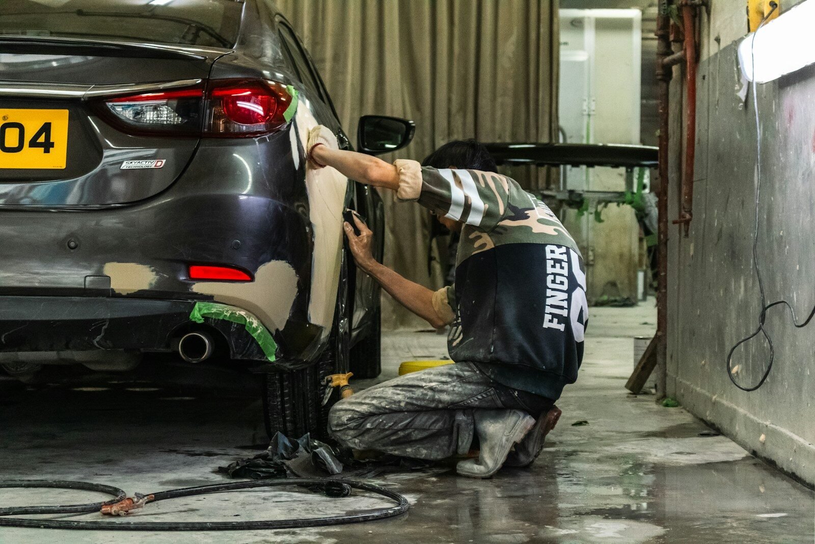Panel beater sanding car bumper in Canberra